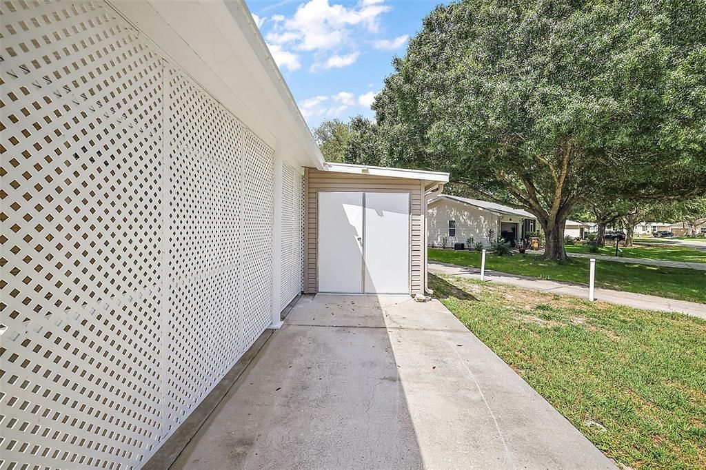 Side driveway for golf cart parking. Double doors to garage, currently used as a workshop.