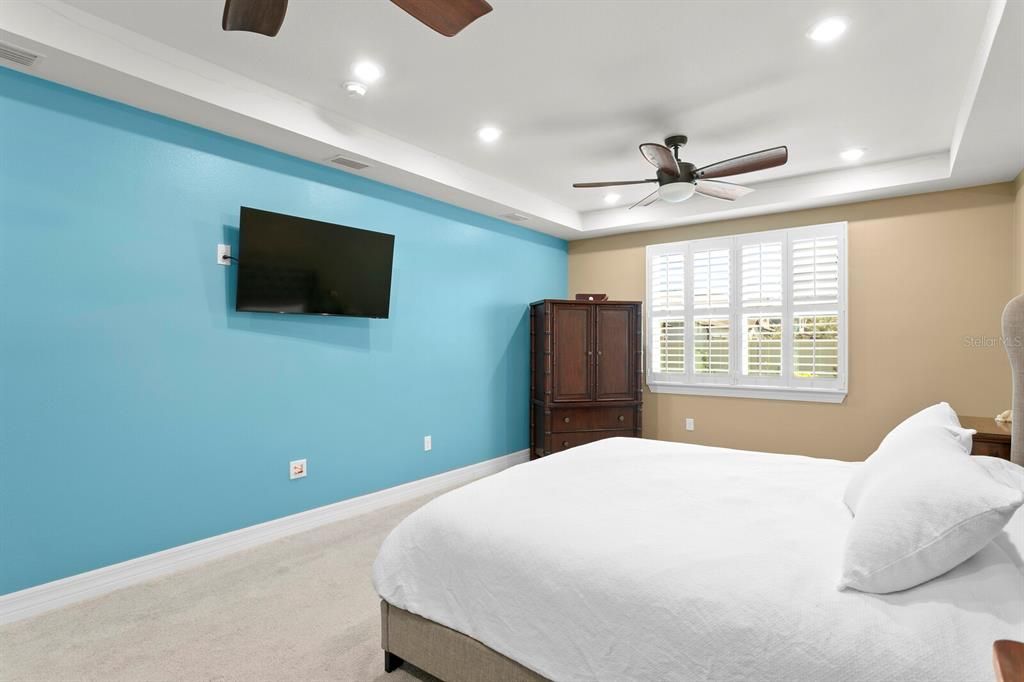 The master bedroom features decorative tray ceilings, dual ceiling fans and recessed lighting