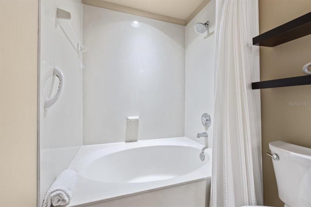 renovated primary bathroom with dual vanities, and a garden tub.