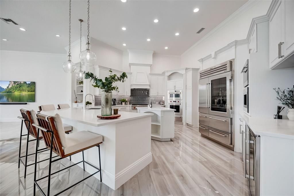 The home chef will revel in the stainless steel Wolf appliances, crafted cabinetry for endless storage, center island with prep sink, sleek countertops and walk-in pantry - all with the sweeping water views!