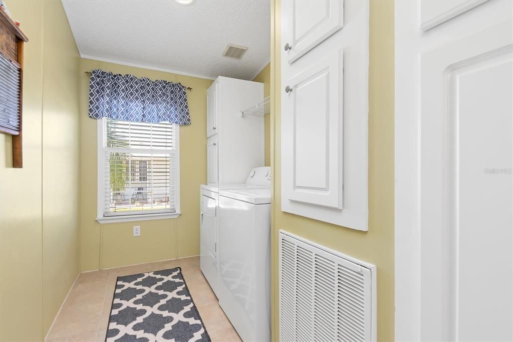 Generously sized laundry room with storage cabinets.