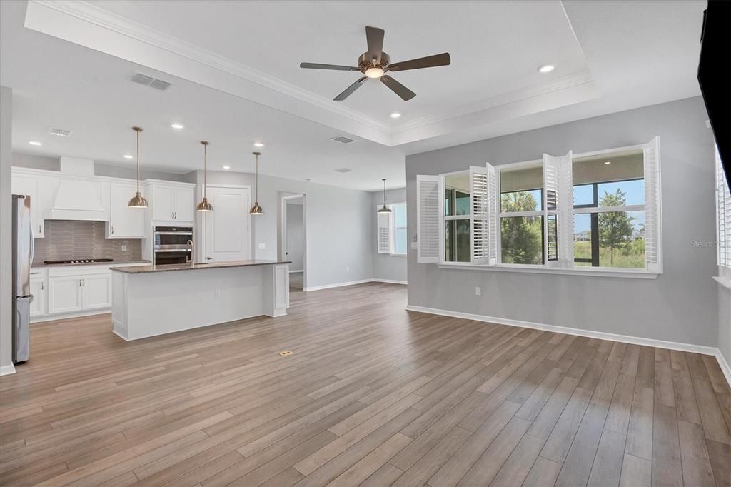 Photo shows warm luxury vinyl plank floor, Plantation shutters, big kitchen island with pendants/ all furnishings belong to tenants