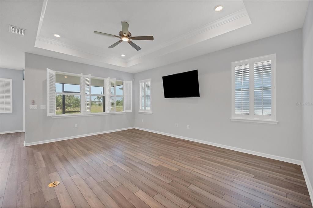 The Gathering Room with Luxury vinyl plank for easy maintenance. Coffered ceiling with crown molding- Plantation shutters, ceiling fan and TV convey with the home
