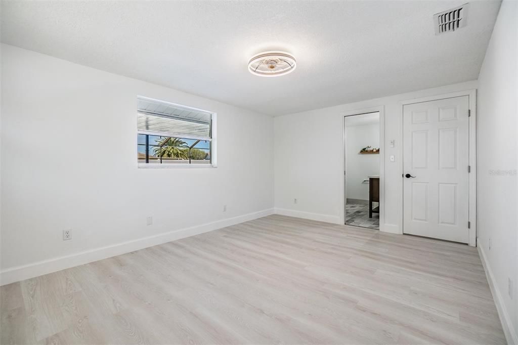 Primary Bedroom with light and fan and entrance into bathroom