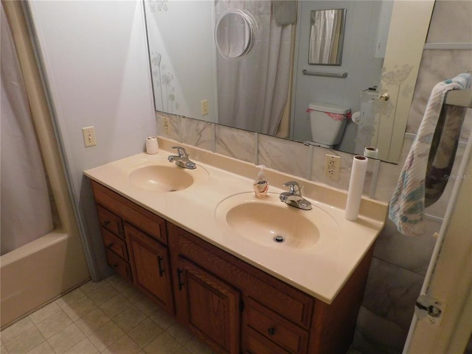 Guest bathroom has double vanity, tub/shower combo, and high toilet.