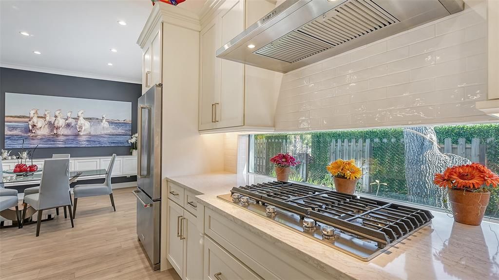 The meticulously designed kitchen features all stainless appliances, 5 burner gas range, Quartz island and counters, ample walk-in pantry and outdoor vistas