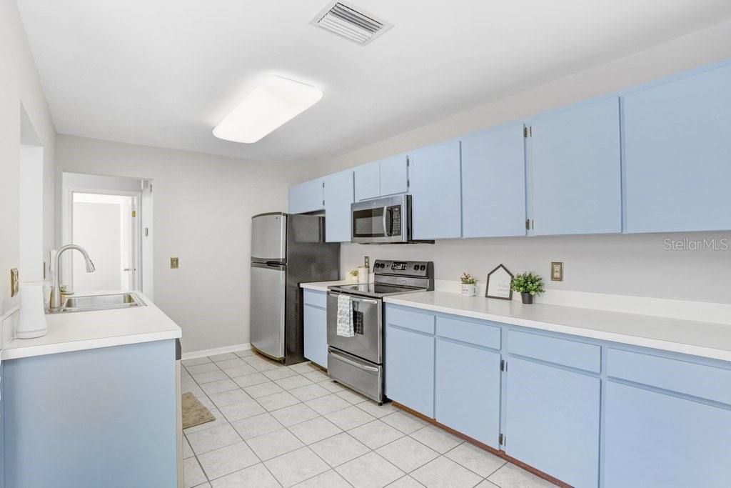 The kitchen is large, has an eat-in area with a view of the front porch, lots of counter space, ceramic tile flooring, stainless appliances, dishwasher, disposal, a closet pantry, and a pass-through to the dining room.