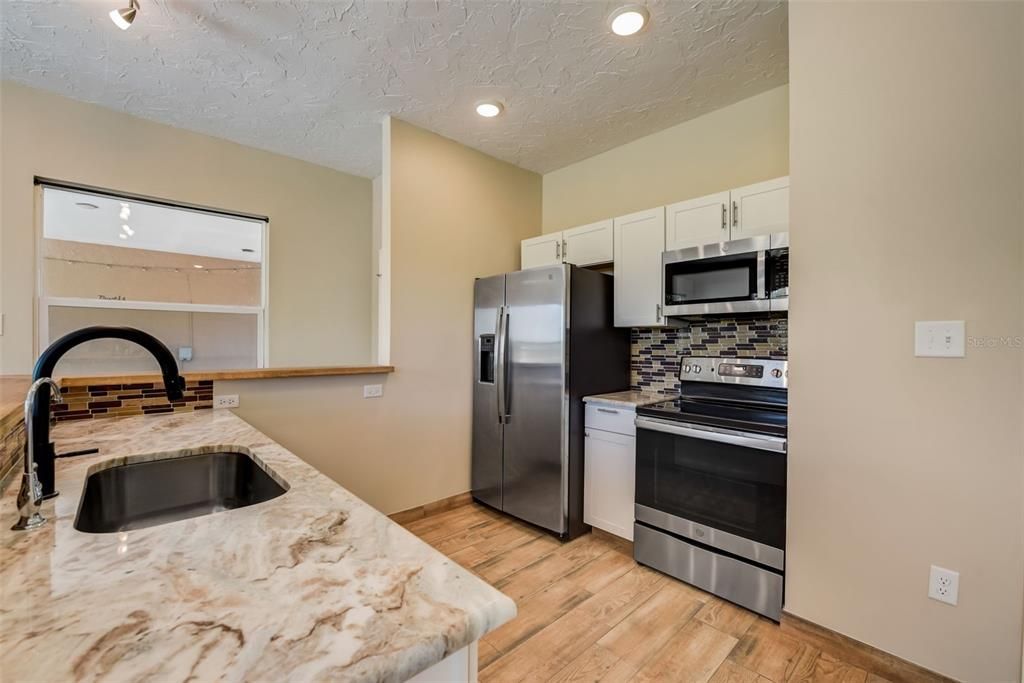 3rd Kitchen with all appliances including stove, dishwasher, refrigerator and microwave. Featuring white cabinets and granite counters and porcelain tiled floors throughout