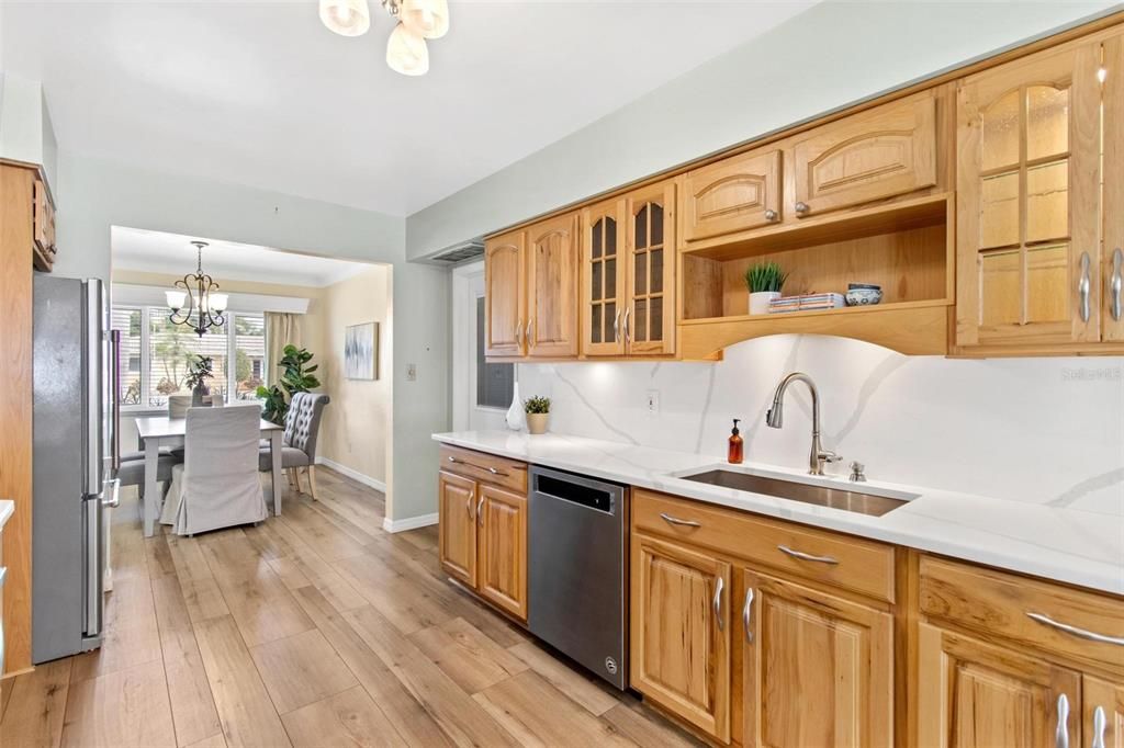 Galley kitchen has solid wood cabinetry, under-mount lighting, quartz countertops and stainless steel appliances