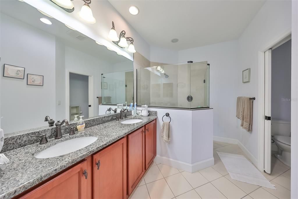 Primary bathroom - solid wood cabinets, granite counters, dual sinks, new shower, recessed lighting and private water closet.