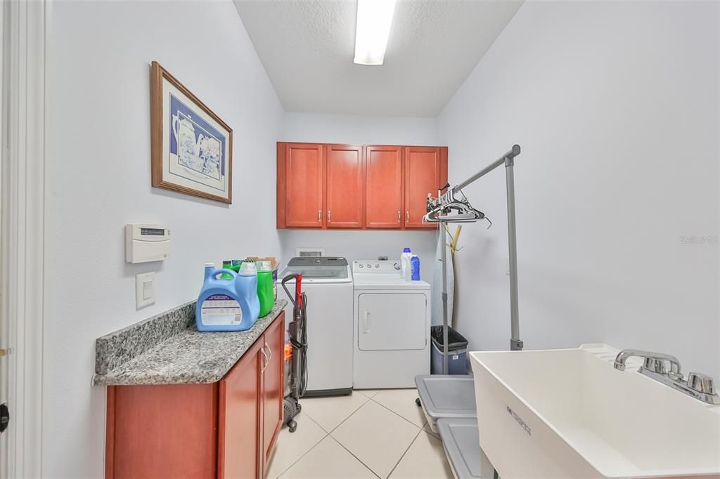 Laundry Room with solid wood cabinets, washer, dryer, granite counter, utility sink