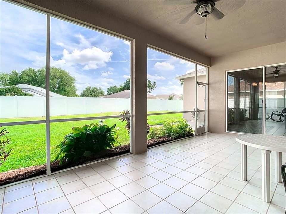 Spacious screened and covered patio overlooks a fenced back yard