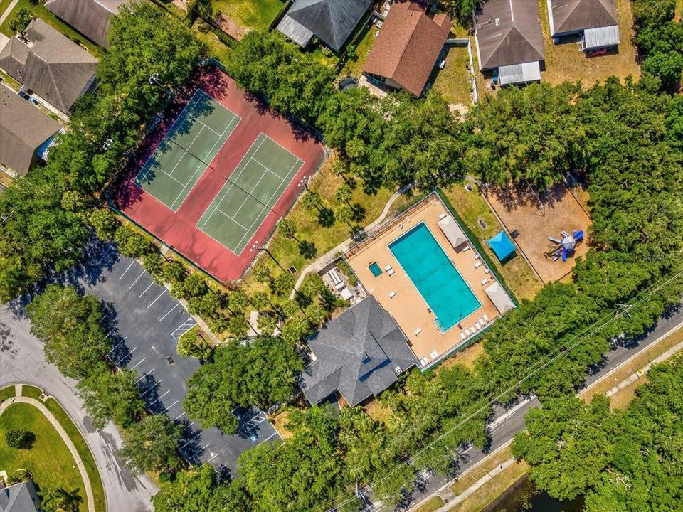view of tennis courts, pool, playground, clubhouse & parking