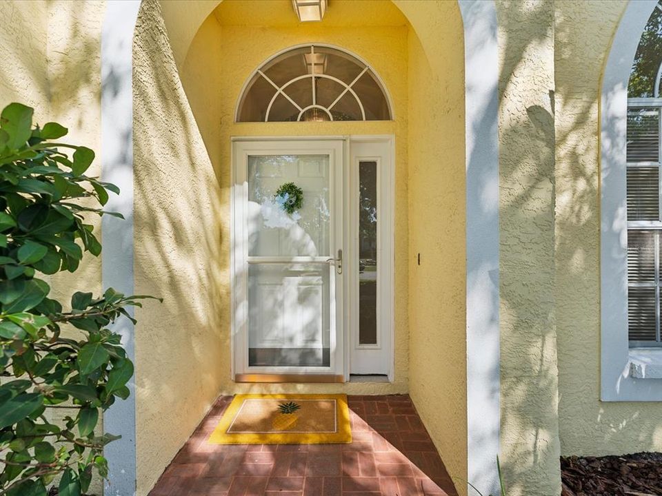 covered front entry with storm door, side light and fan light.