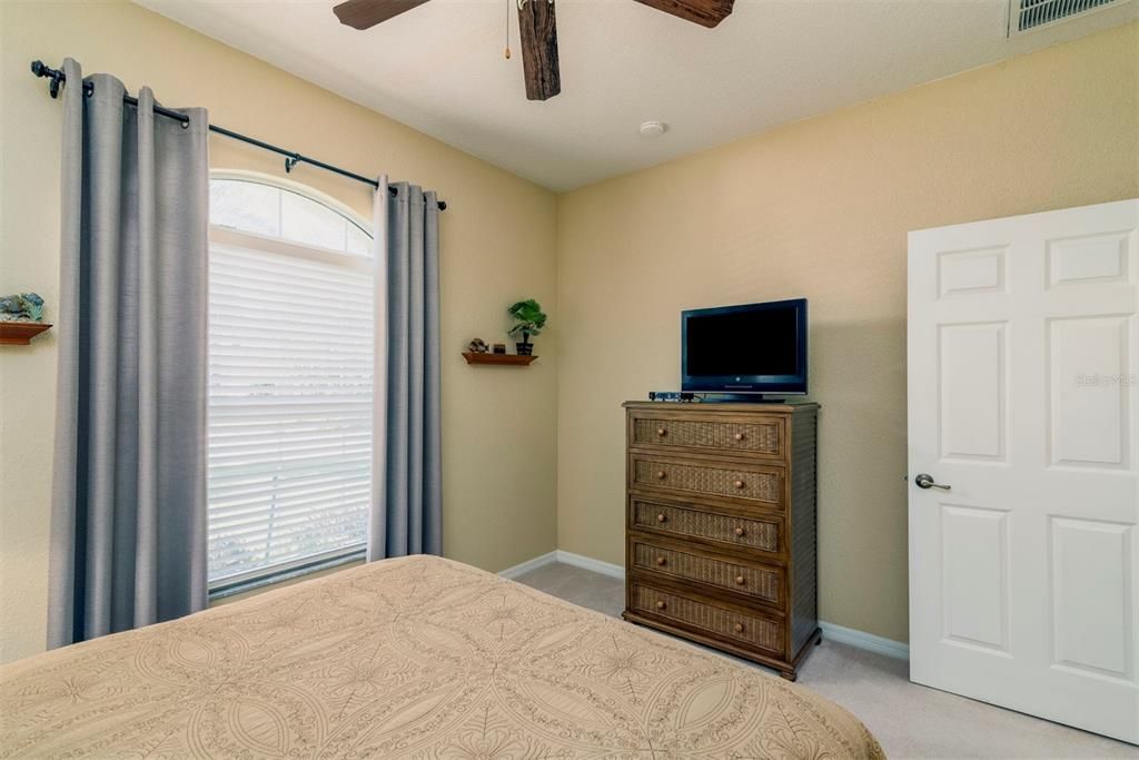 The guest bedroom has an arched window that adds class to this space. The window treatments stay!