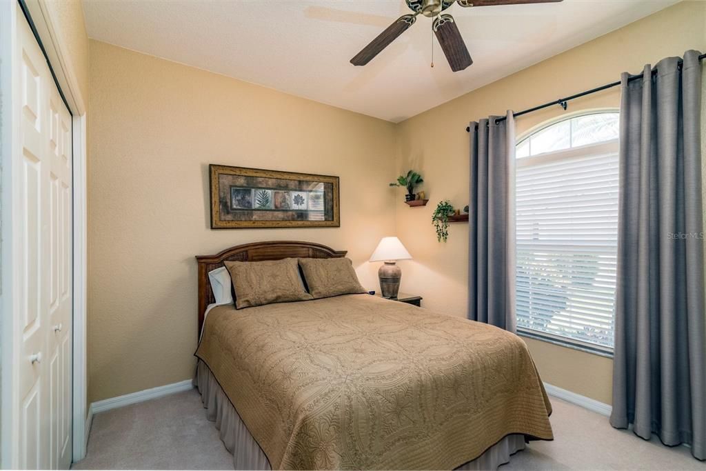 The guest bedroom is at the front of the home and has an arched window, ceiling fan, newer carpeting, and a reach in closet.