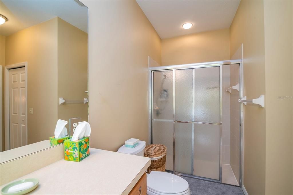 The master bath has an elongated stool and a stall shower with shower door and ceramic tile surround.