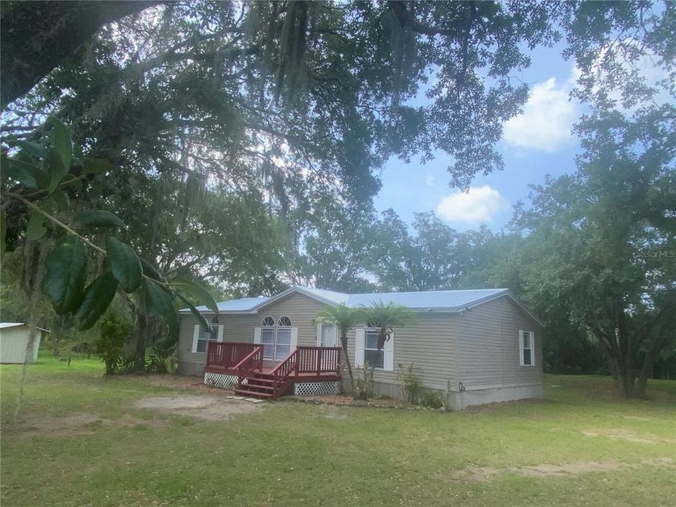 Home has a new 26 guage metal roof. Front view of the mobile home shows the large patio deck.