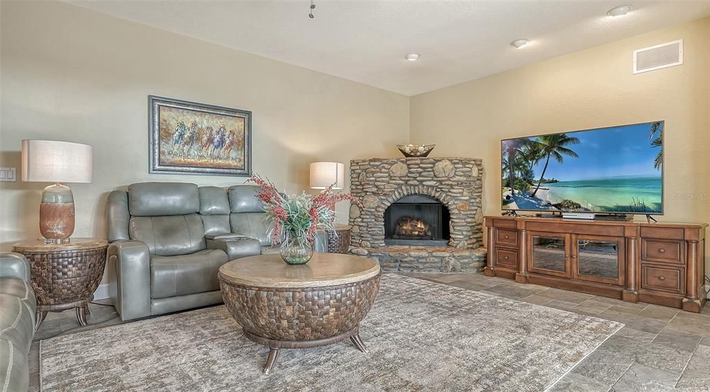 The gathering room features an electric fireplace that matches the outdoor summer kitchen stone work.