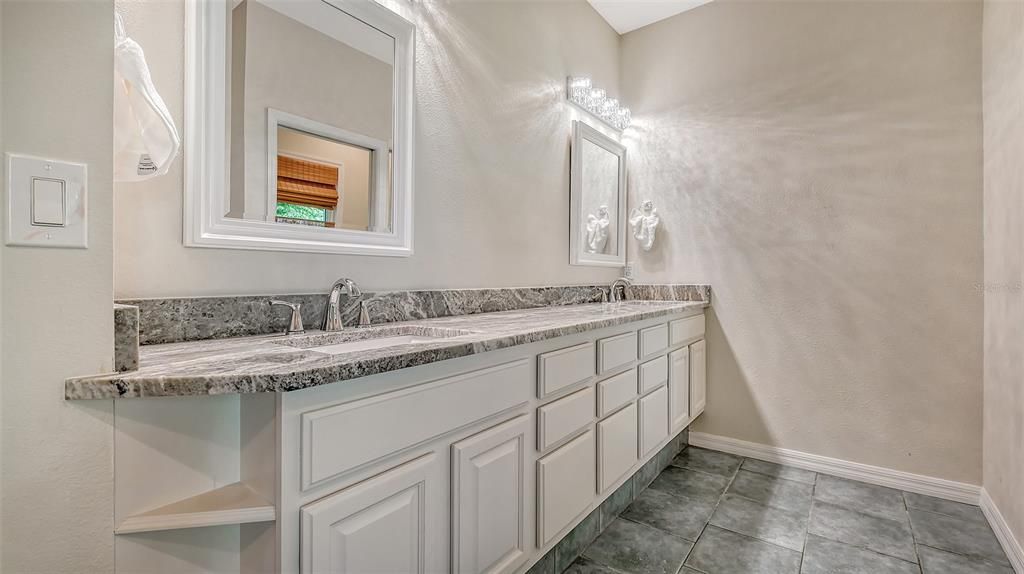 The Primary Suite Bathroom has granite countertops and double sinks.