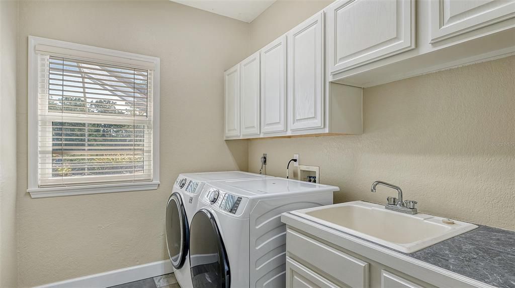 The laundry room features 2022 front load washer and dryer, plus a good sized sink as well as cabinets top and bottom.