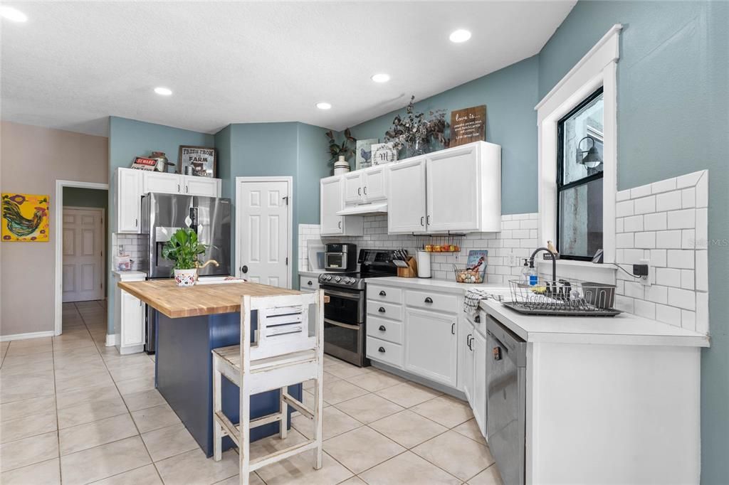 Kitchen with large island, separate sink, tiled floors and window overlooking lanai/patio