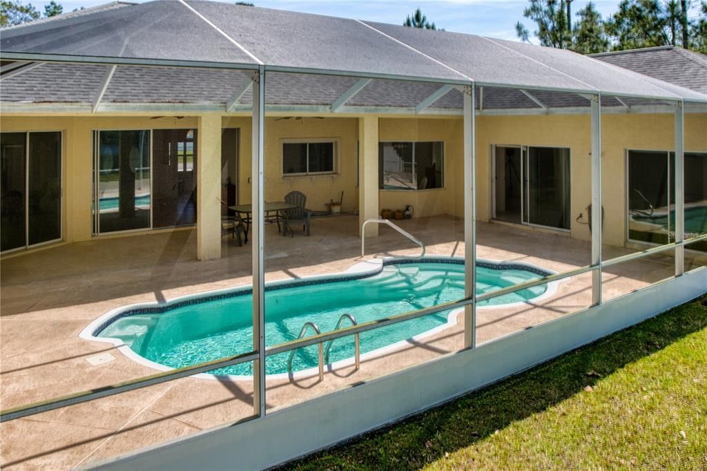 This home features a large screened pool cage, providing the perfect blend of outdoor enjoyment and indoor comfort. This enclosure ensures a bug-free environment, allowing you to relax or entertain by the pool any time of day without the inconvenience of insects. The screen also filters sunlight, reducing the intensity while still letting you bask in the warmth and glow of natural light. This setup enhances the usability of the pool area, making it an ideal place for year-round swimming, lounging, and social gatherings in complete comfort.