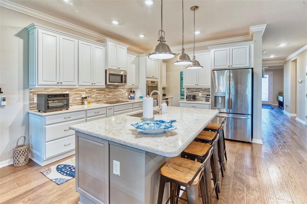 This is a chef's delight! GOURMET KITCHEN, upgraded cabinets, LARGE island with pendants, quartz counters, custom backsplash, under AND UPPER cabinet lighting