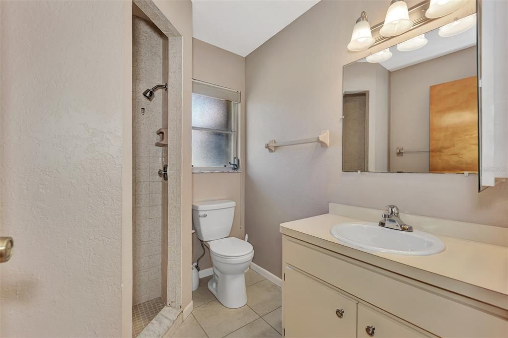 En suite bathroom has single vanity and tiled shower.