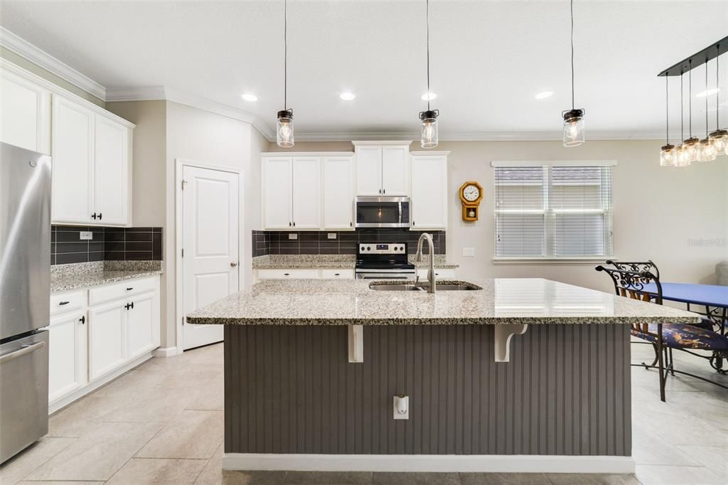 The home chef will delight in the well appointed kitchen delivering a chic color palette of 42” cabinetry topped with crown molding, subway tile backsplash, STAINLESS STEEL APPLIANCES, walk-in pantry, GRANITE COUNTERS and a large ISLAND with additional breakfast bar seating.