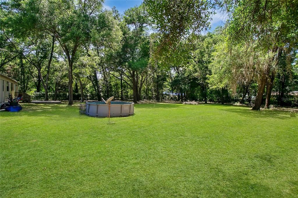 This is a view of the back yard of the property, from the right side, and shown is the above ground pool and a spacious area for all kinds of hobbies and activities.