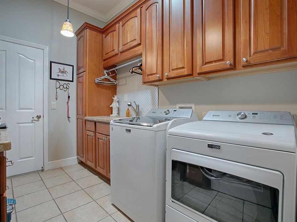 Laundry room with tile flooring, folding area with hanging rack and plenty of storage space