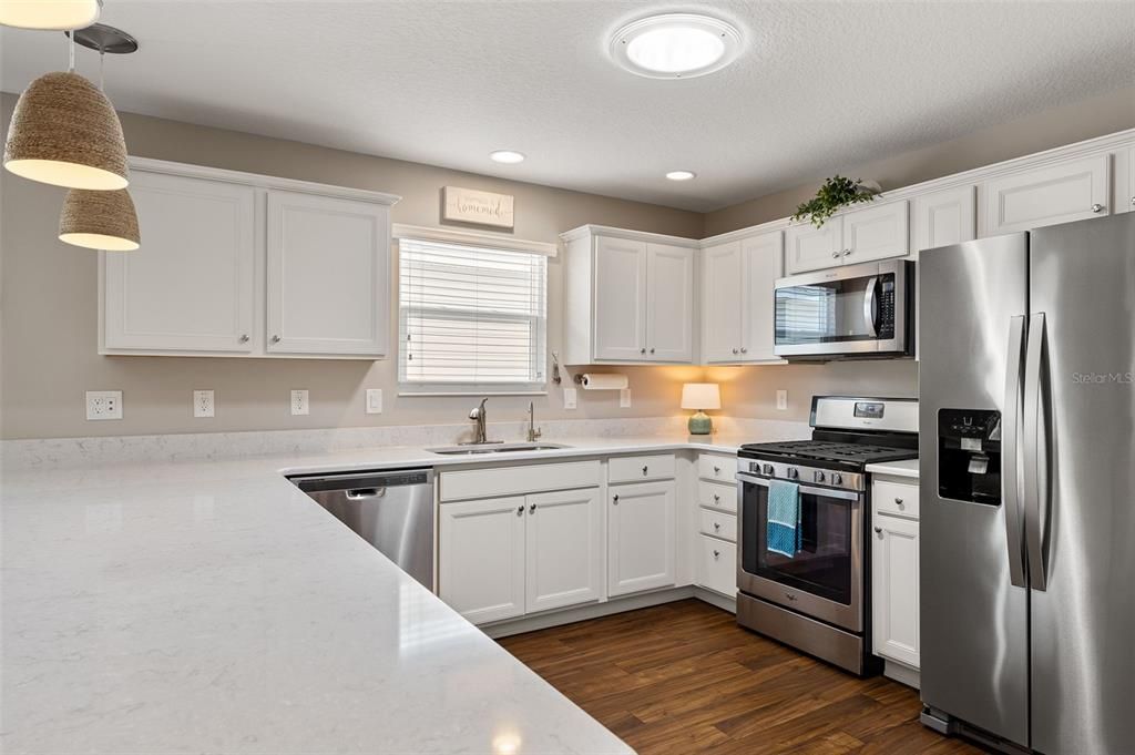 The kitchen is adorned with white cabinets with bottom pull outs and crown molding, QUARTZ countertops, the pantry optimizes storage space with tailored organization solutions.