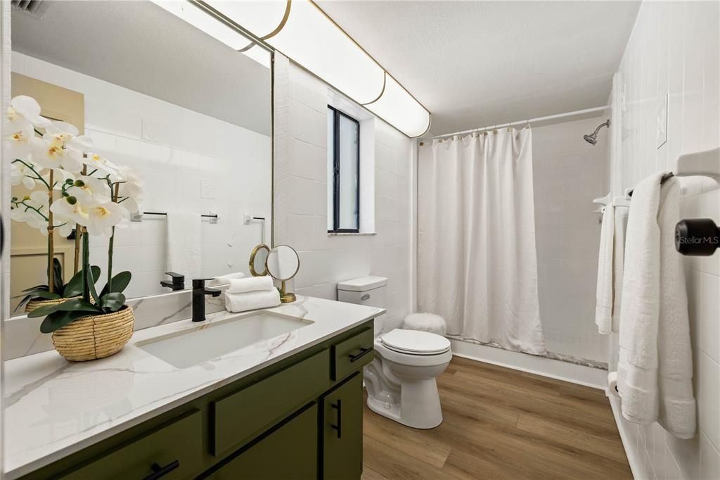 Primary bathroom with walk in shower and quartz countertop on the vanity