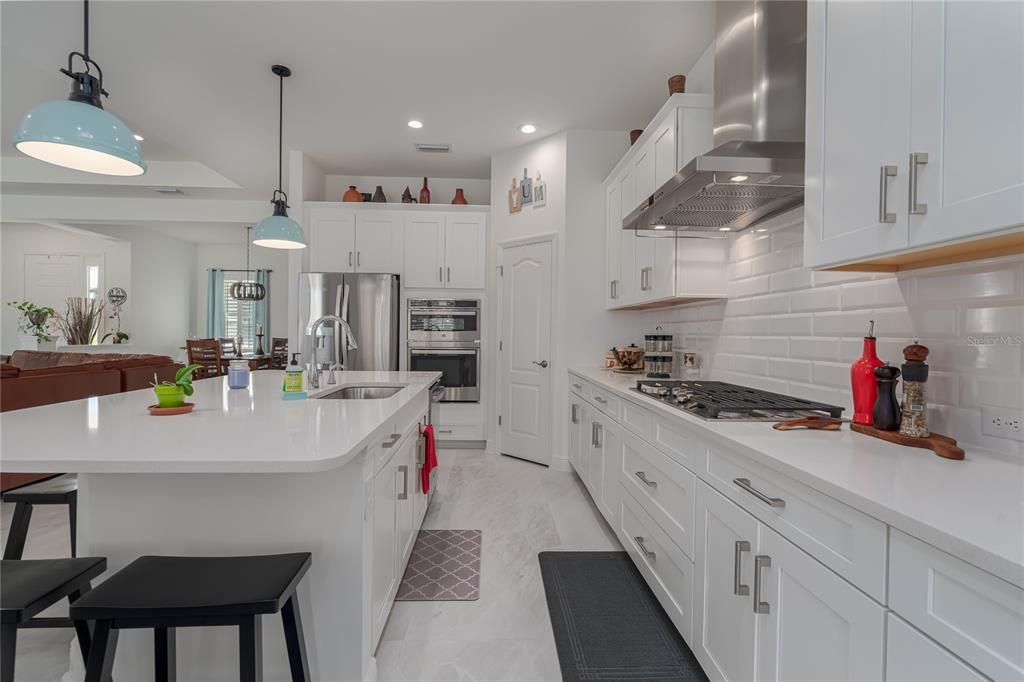 Kitchen with quartz countertops, large island, stainless appliances, walk-in pantry, soft close cabinets, and gas cooktop with hood