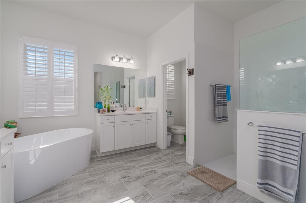 Primary Bathroom with stand alone tub, walk-in shower, split vanities, and private water closet