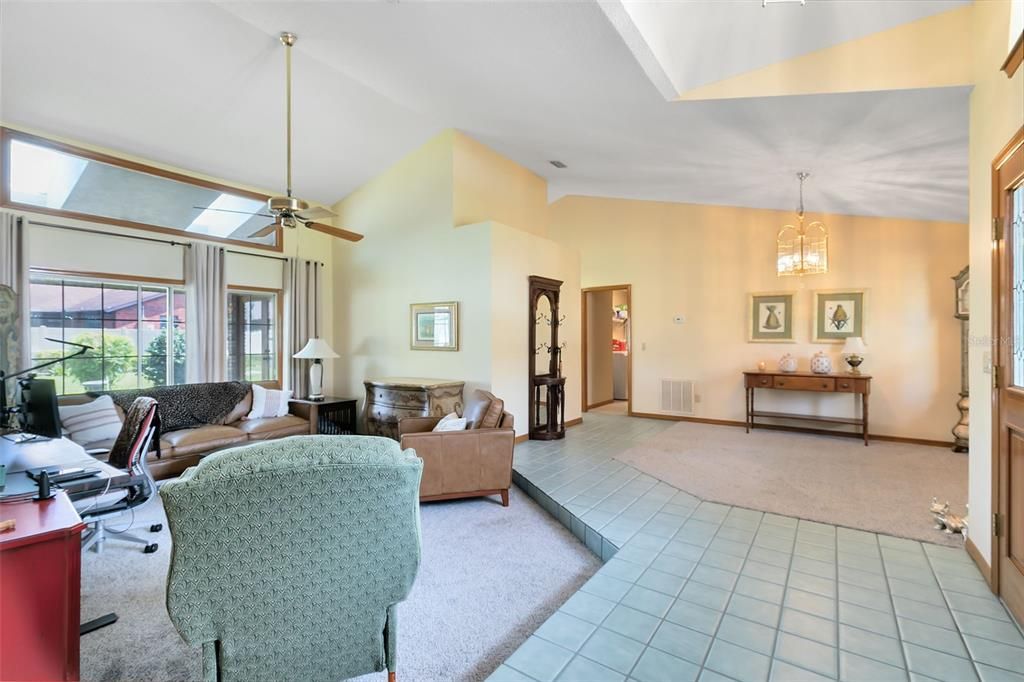 A soaring vaulted ceiling graces both the formal living room and adjacent formal dining area.