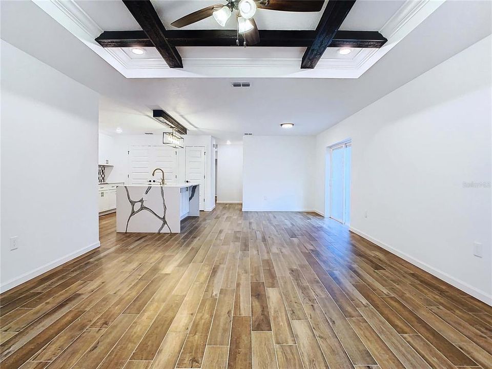 Great room with wood-look tile floors and decorative beams overhead
