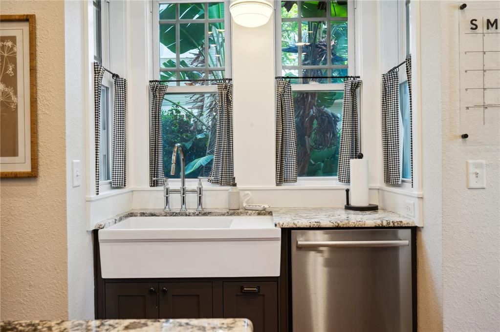 Farmhouse apron sink with panoramic views of beautifully landscaped side yard and window access to side deck