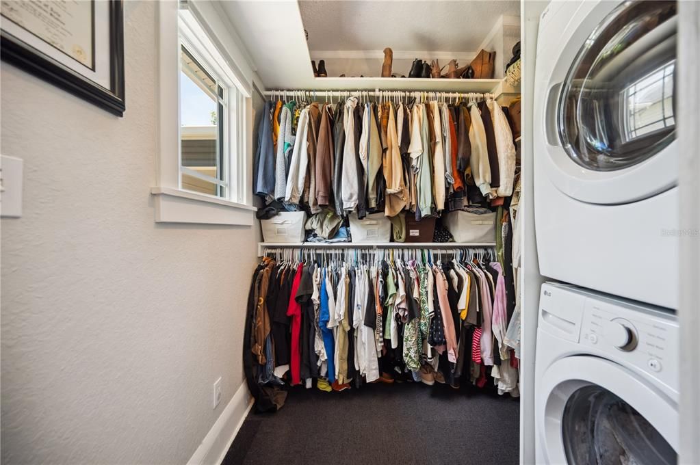 Primary bedroom walk-in closet with convenient stackable laundry included in the sale (7x7ft space). Additional closet space not shown behind the washer and dryer. Primary bedroom also features a separate shoe closet with pull out shelving AND a large utility storage closet