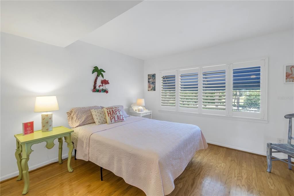 Second bedroom with plantation shutters and wood floors