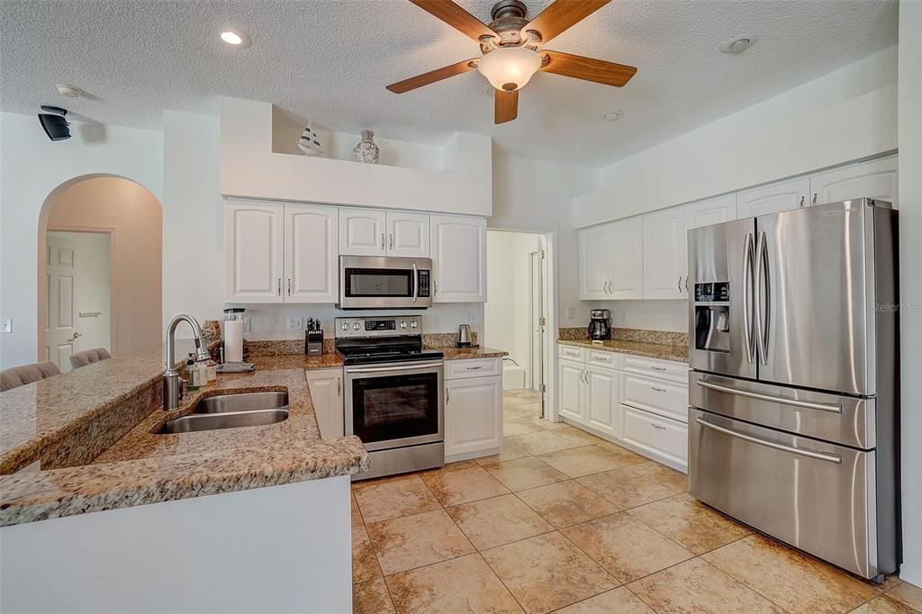 Light bright kitchen with stainless steel appliances, beautiful countertops and easy maintenance tile flooring