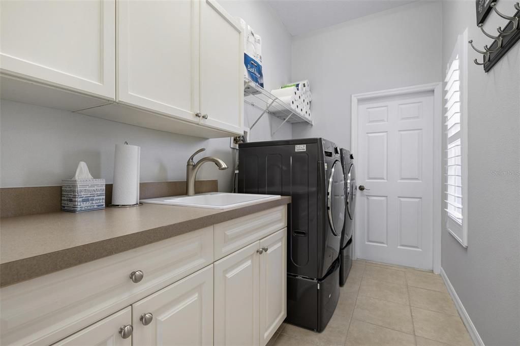 Extra large laundry room with sink and built-in cabinets. Door leads to 3 car, side entry garage