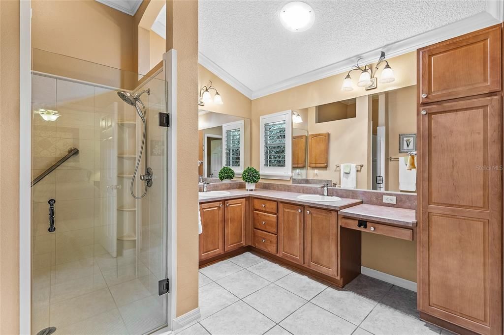 Primary bath room with dual sinks, dressing table, large walk-in shower, crown molding, solar tube, large walk-in closet.