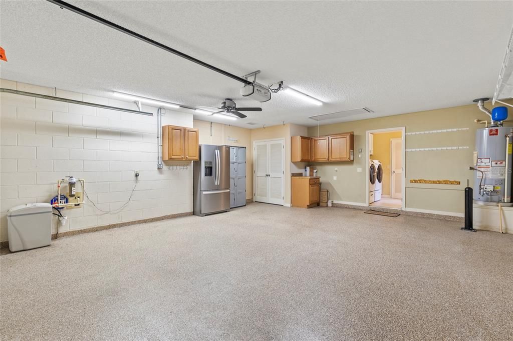 Oversized 2 car garage with epoxy coated floor, fan, pull down attic stairs with plywood flooring in attic, water softener system, stainless steel refrigerator, cabinets for storage.