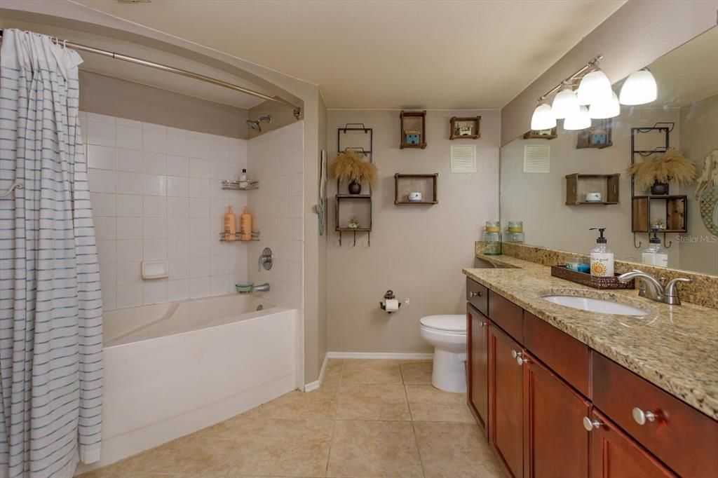 Primary ensuite with tub/shower combination and spacious granite-topped vanity