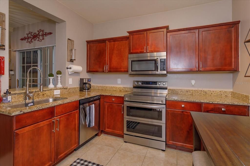 11' x 10' kitchen with wood cabinetry, stainless appliances and granite countertops