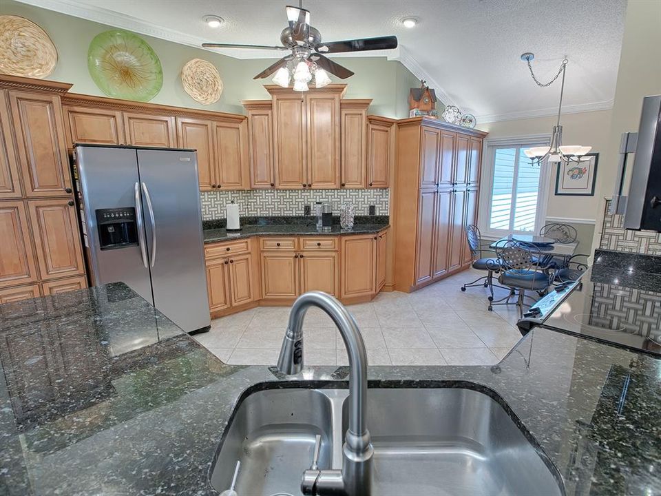 GRANITE COUNTERS AND LOVELY CUSTOM BACKSPLASH! PANTRY AND MORE CABINETS STORAGE SPACE TO THE LEFT OF THE REFRIGERATOR.