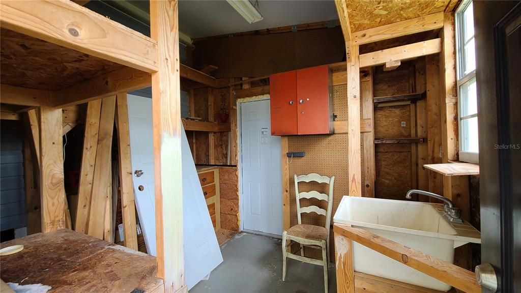 Outside storage shed with workbench and wash tub.