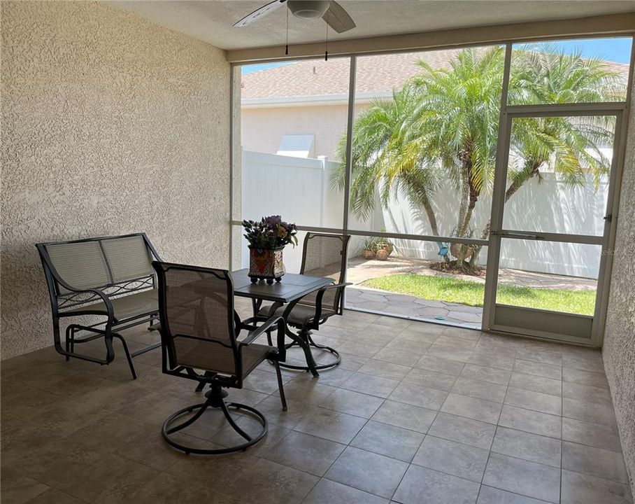 Covered back porch, screened-in, tiled flooring, with tropical setting.